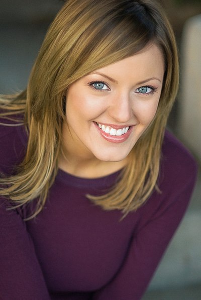 Smiling person wearing a plum-colored top against a softly blurred background.