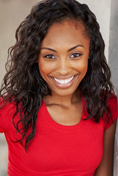 Smiling person with long dark hair wearing a red top.